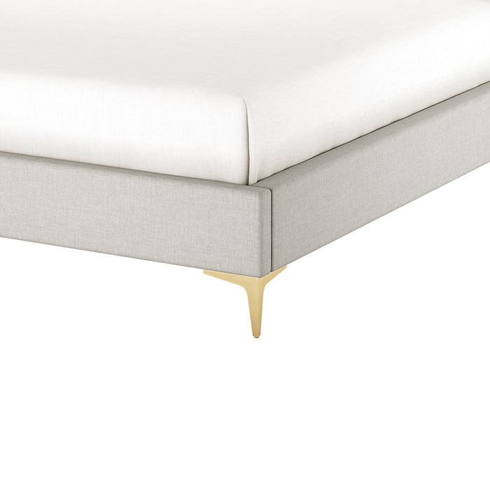 Corner detail of grey fabric bed frame with brass leg, white mattress