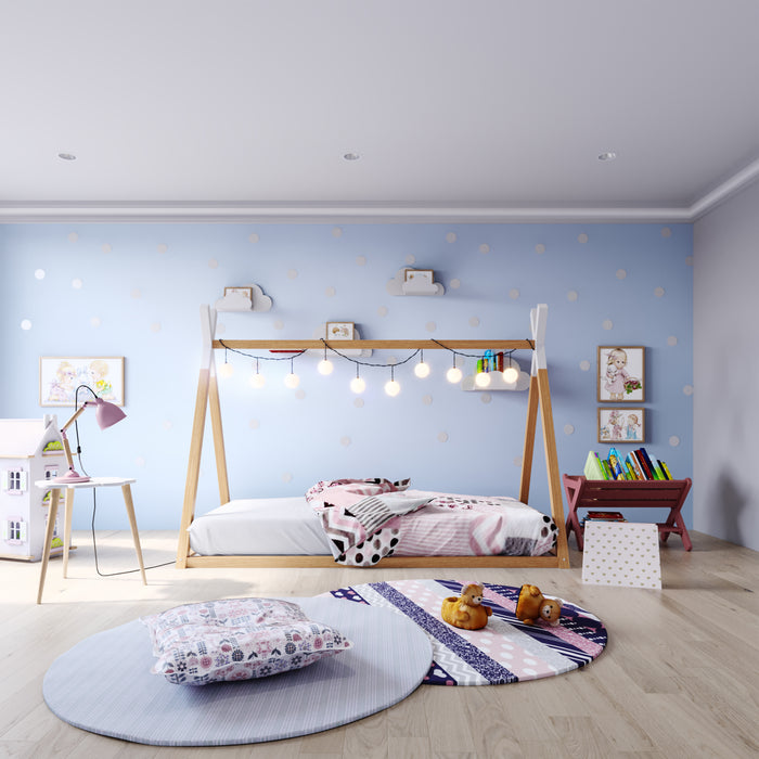 Helena Kids Single Solid Pine Teepee Bed Frame in Natural, featuring a wooden house design draped with string lights, set against polka dot walls, surrounded by playful children's decor and accessories.