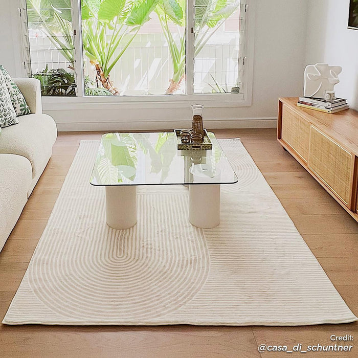 Krokom 160x230cm Modern Abstract Indoor Floor Rug under a clear glass coffee table, blending seamlessly with the minimalist living room's neutral tones and enhancing its airy, modern ambiance.