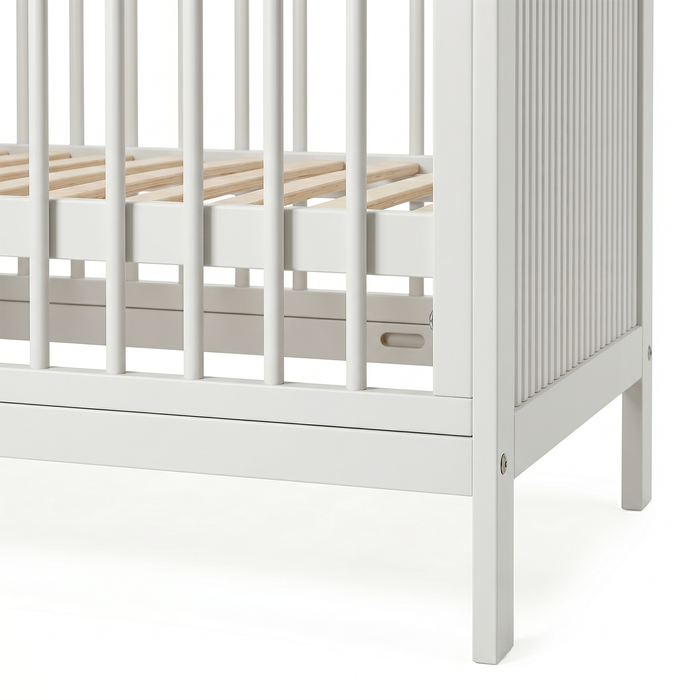 Close-up of white crib corner and slatted side on white background