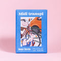 A blue box labeled Midi Transpi | 100 Piece Jigsaw Puzzle by Jour Férié features a bike and orange car; ribbon cut and made in France.