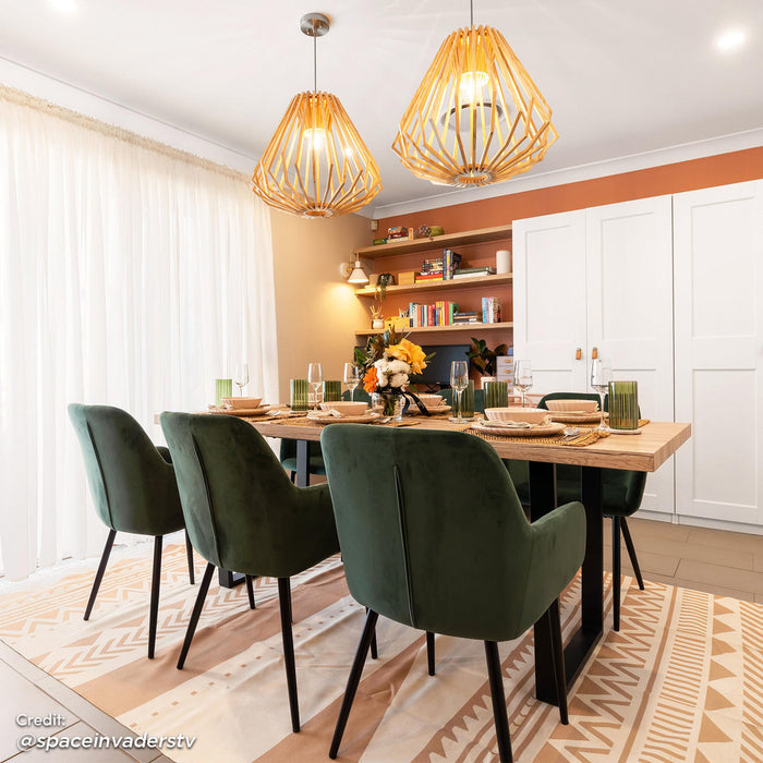 Raynie Velvet Dining Chair Set of 2 in Deep Green, featuring plush velvet upholstery, slim black legs, and positioned around a light-wood table in a warmly-styled dining room, enhancing modern elegance.