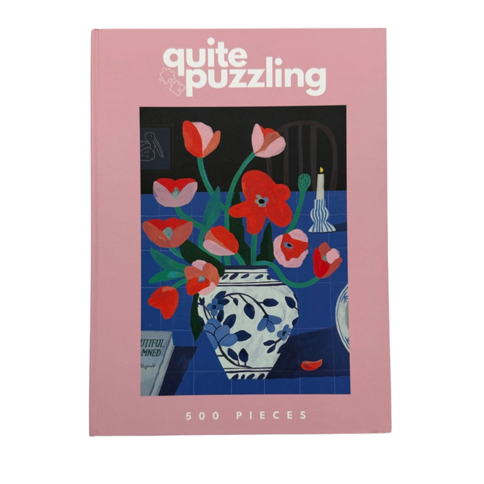 A 500-piece jigsaw puzzle by Quite Puzzling, “Table For Tulip,” with a pink cover featuring red flowers in a blue and white vase—perfect as a coffee table display or for puzzling enjoyment.