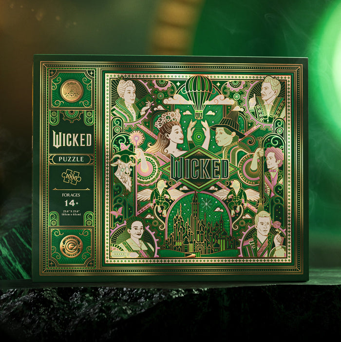 The theory11 Wicked | 1,000 Piece Jigsaw Puzzle comes in a decorative box with Emerald City artwork, illustrated characters, a hot air balloon, and green-gold accents. Suitable for ages 14+.